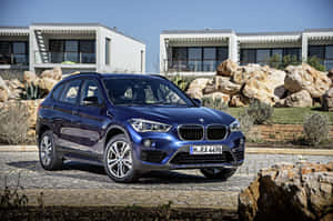 藍色BMW X1 SUV停泊在現代房屋前，有沙漠岩石和晴朗天空。 — Mercedes Benz C300 壁紙