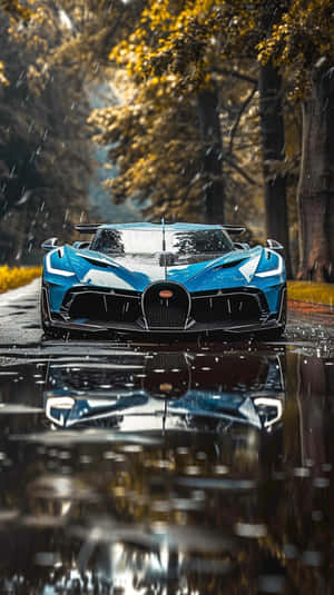 藍色 Bugatti 跑車停放在有秋樹和水面倒影的雨中森林道路上。 — 布加迪 GIF 壁紙