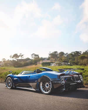 藍色Pagani Zonda跑車停泊在風景優美的道路上，背景有綠色山丘。 — Apple Watch Ultra 壁紙