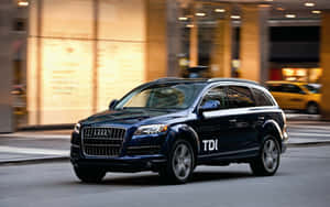 深藍色Audi Q7 TDI SUV夜間在城市街道上行駛。 — MacBook Pro 13 壁紙