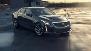 深灰色Cadillac CTS-V轎車在日落時停放在裂開的混凝土上。 — 凱迪拉克 壁紙