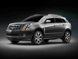 一輛深灰色 Cadillac SRX SUV 在工作室中，帶有戲劇性燈光。 — 凱迪拉克 壁紙