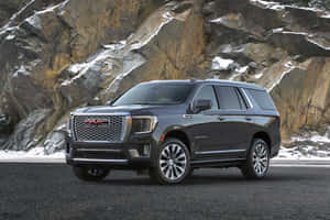 深灰色GMC Yukon Denali SUV停泊在積雪山坡附近。 — MacBook Air 壁紙