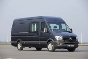 深灰色 Mercedes-Benz Sprinter 客貨車停放在鋪砌場地上，背景有風力發電機。 — Mercedes Benz C300 壁紙