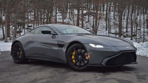 灰色 Aston Martin 跑車，黃色制動器，停泊在森林附近的積雪道路上。 — 奧斯頓馬丁 壁紙
