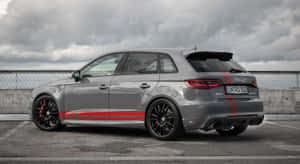 灰色奧迪RS3 Sportback，帶有紅色條紋，停在多雲天空下的屋頂上。 — 奧迪 GIF 壁紙