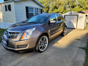 灰色Cadillac SRX停放在房屋和棚屋附近的混凝土車道上。 — 凱迪拉克 壁紙