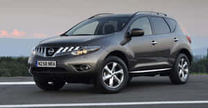 灰色日產Murano SUV在暮色中停在路上，遠處有樹木和山脈。 — 日產 壁紙
