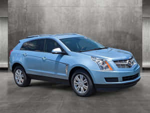 淺藍色 Cadillac SRX SUV 停放在灰色混凝土牆前。 — 凱迪拉克 壁紙