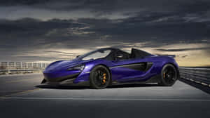 紫色McLaren 570S Spider敞篷跑車在黃昏時於暴風雨天空下的高速公路上。 — Pro Display XDR 壁紙