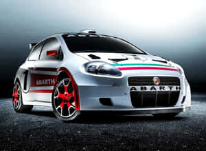 銀色 Abarth 拉力賽車，帶有紅色車輪和義大利國旗條紋，停在深色瀝青上。 — 飛雅特 壁紙