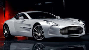 銀色Aston Martin跑車在黑暗的攝影棚中，紅色燈光下車頭燈閃爍。 — 奧斯頓馬丁 壁紙