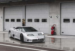 銀色Bugatti跑車停在帶有編號的車庫門前，路面潮濕。 — 布加迪 GIF 壁紙