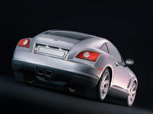 銀色 Chrysler Crossfire 跑車從後方四分之三角度在深色攝影棚中觀看。 — OLED 壁紙