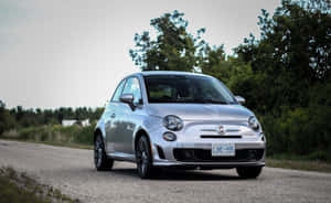 銀色Fiat 500在碎石路上，周圍環繞著樹木。 — Steam Deck 壁紙