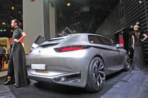 銀色未來感汽車在車展上與穿著晚禮服的模特一同展出。 — Surface Laptop 壁紙