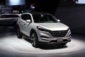銀色現代 Tucson SUV 在車展上以聚光燈展示。 — 起亞 壁紙