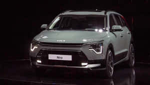 銀色Kia Niro SUV在黑暗舞台上，有聚光燈和地板反射。 — 起亞 壁紙