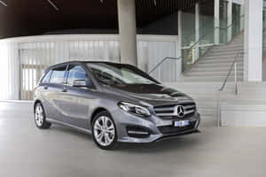 銀色 Mercedes-Benz B-Class 停放在現代建築中，設有混凝土樓梯和玻璃欄杆。 — Mercedes Benz C300 壁紙