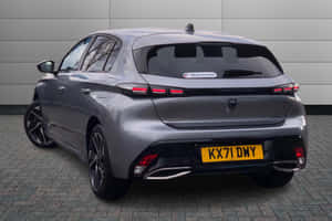 銀色Peugeot 308掀背車停在行人路上，灰色牆壁背景。 — MacBook Air 15 壁紙