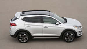 白色現代 Tucson SUV 從上方俯瞰停在灰色瀝青上。 — 富豪 壁紙
