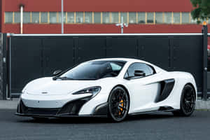 帶有黑色細節的白色McLaren跑車停在紅樓附近的人行道上。 — MacBook Pro M4 壁紙
