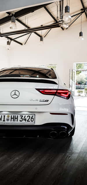 白色 Mercedes-AMG CLA 45 S 在現代車庫中，深色木地板和吊燈。 — Nokia C210 壁紙