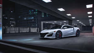 白色跑車配紅色制動器，夜間停放在光線昏暗的城市停車庫中。 — Acura 壁紙