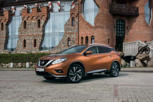 銅色日產Rogue SUV停放在城堡風格的磚砌建築前，配有玻璃窗。 — 日產 壁紙