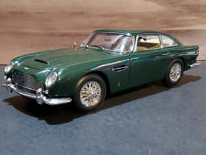 綠色Aston Martin DB5模型車，帶有鍍鉻細節，置於深色表面。 — 奧斯頓馬丁 壁紙