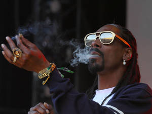 Snoop Dogg 戴著金色太陽眼鏡和珠寶呼出煙霧。 — 史努比狗狗 壁紙