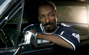 Snoop Dogg 從車窗中探出頭來，帶有金色背光。 — 史努比狗狗 壁紙