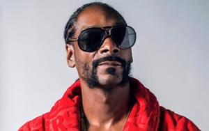 Snoop Dogg 身穿紅色連帽衫和太陽眼鏡，為工作室肖像擺姿勢。 — 史努比狗狗 壁紙