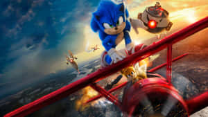 Sonic the Hedgehog 和 Tails 駕駛一架紅色雙翼飛機，Dr. Eggman 在夕陽天空下追趕他們。 — 音速小子 壁紙