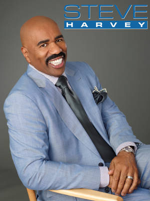 身穿藍色西裝的 Steve Harvey 對著鏡頭溫暖微笑。 — 湯姆貓與傑利鼠 iPhone 壁紙
