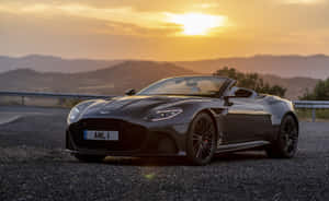 黑色Aston Martin敞篷車停泊在碎石路上，金色日落。 — MacBook Pro 13 壁紙