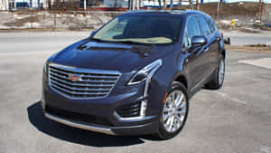 深藍色Cadillac XT5 SUV停在建築工地附近的柏油路上。 — 凱迪拉克 壁紙