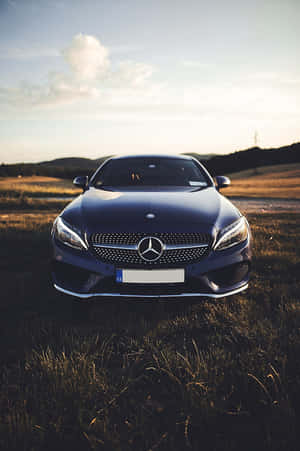 日落時分，一輛深藍色賓士轎車停泊在草地上。 — Mercedes-Benz 壁紙