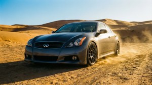 灰色 Infiniti 轎車在日落時分於沙漠沙丘上疾馳。
