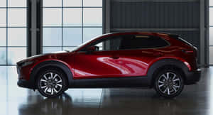 紅色Mazda CX-30 SUV停放在設有大窗戶的明亮工業車庫內。 — 馬自達 壁紙