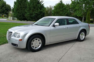 銀色Chrysler 300轎車停在混凝土車道上，後面有綠化。 — Surface Pro 壁紙