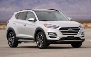 白色現代 Tucson SUV 停放在戶外，靠近山脈，天空多雲 — Steam Deck 壁紙