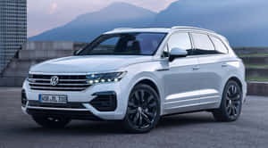 白色福斯 Touareg SUV 在黃昏時停放在山脈附近。 — 福斯汽車 壁紙