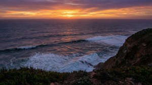 夕陽下的海洋，海浪拍打懸崖