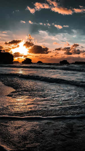 夕陽下的海洋，海浪拍打岩石海岸 — 海灘日落 壁紙