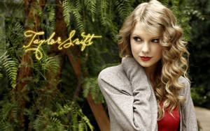 Taylor Swift 身穿灰色外套和紅色上衣，站在蕨類植物中，帶有發光名字文字。 — 音樂 壁紙