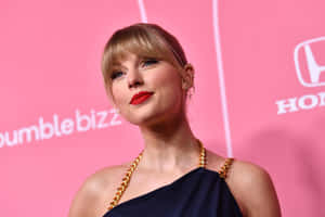 Taylor Swift 在粉紅色品牌活動中，身穿海軍藍連身裙和金鏈。 — 泰勒絲 壁紙
