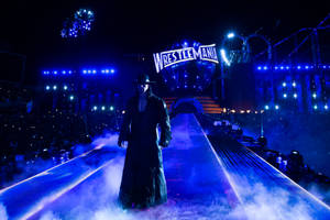 The Undertaker 沿著藍色燈光的 WrestleMania 斜坡走下來，伴隨著霧氣和體育場燈光。 — 送葬者 壁紙