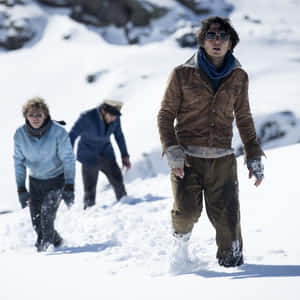 三個人穿著冬季裝備和太陽眼鏡，在雪地山區地形中徒步。 — 雪山 壁紙