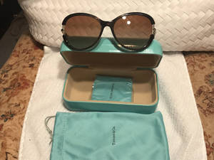 Tiffany & Co. 太陽眼鏡放在藍綠色眼鏡盒和收納袋中，置於白色毛巾上。 — 蒂芙尼藍 壁紙